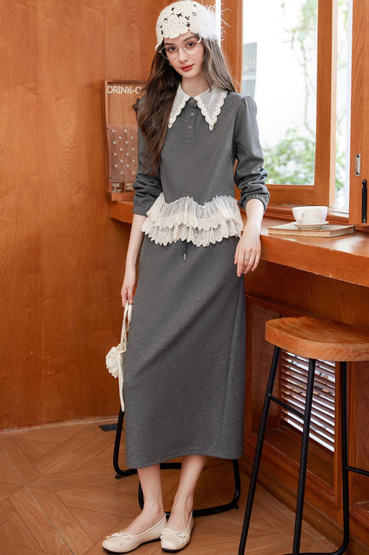 Model in gray lace-trimmed top with matching gray maxi skirt and crochet hat, standing indoors