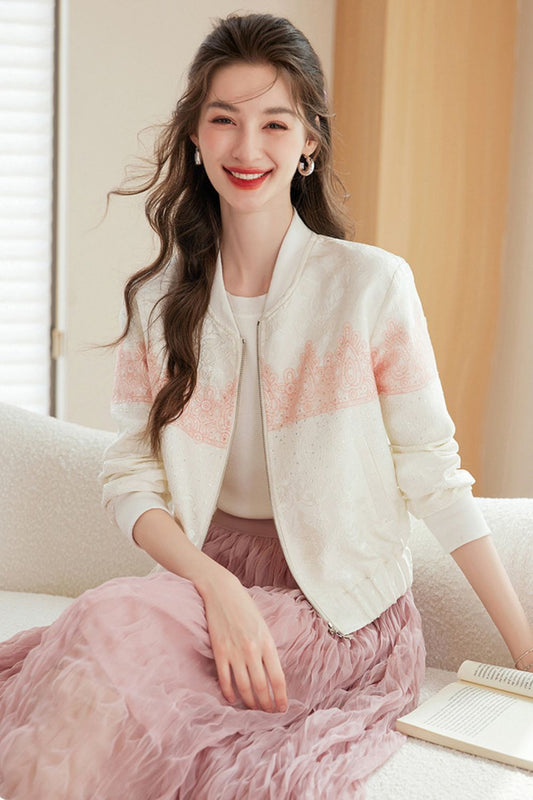 Woman sitting on a sofa wearing a white cardigan with pink details and a pink ruffled skirt, smiling at the camera