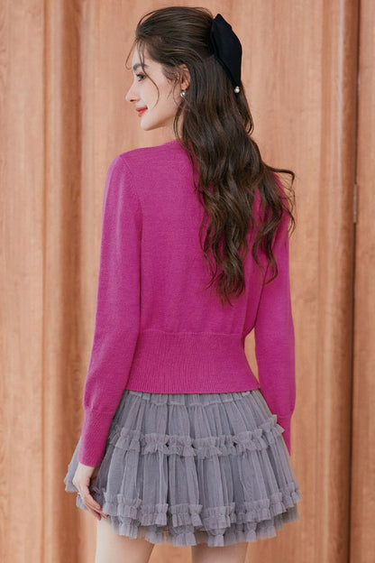 Back view of pink cardigan paired with pleated skirt