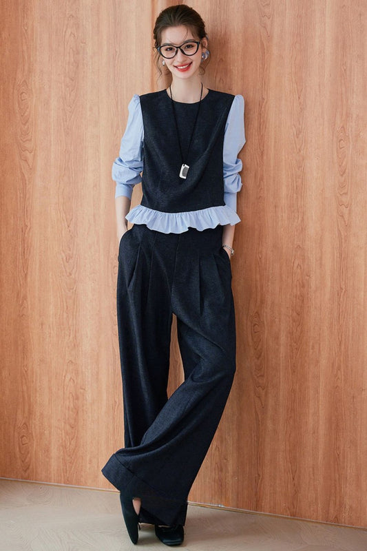Model wearing a layered outfit with a light blue ruffled blouse under a navy blue sleeveless vest, paired with wide-leg navy trousers