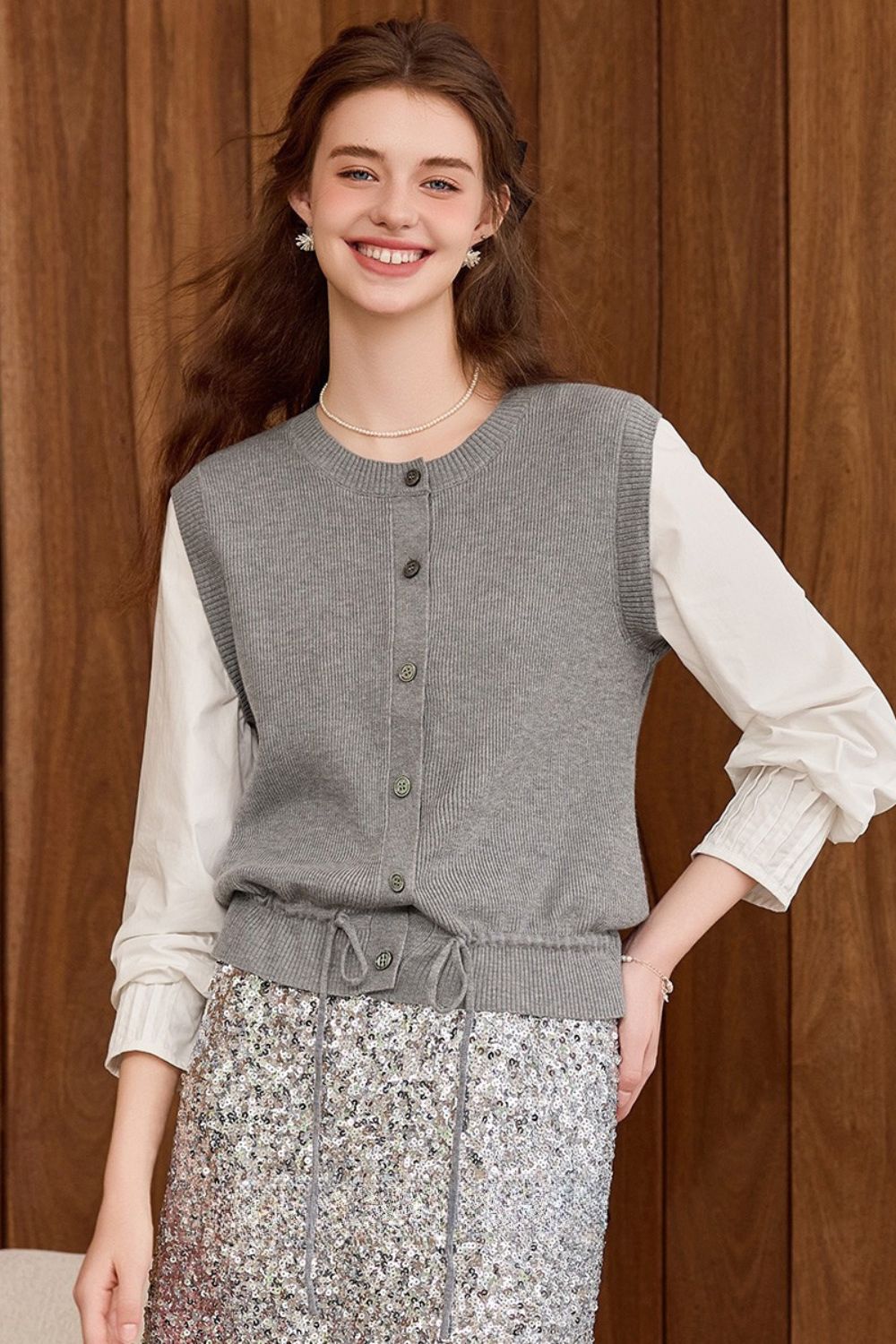 Gray knit vest styled with a white blouse and patterned skirt, front view