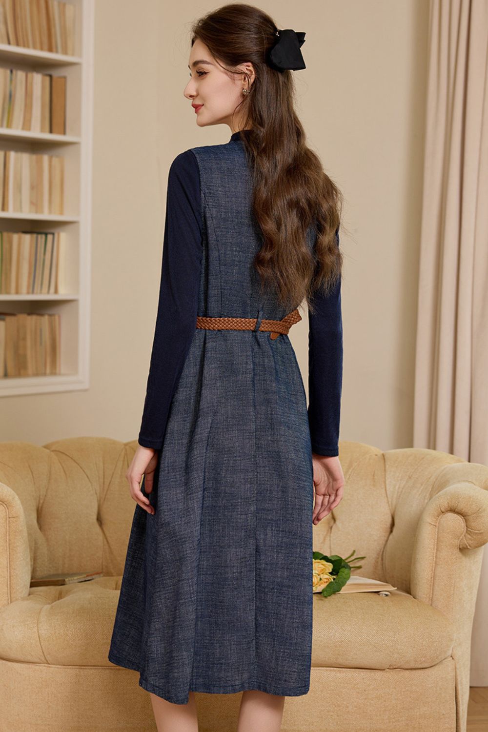 Back profile view of navy denim midi dress with long sleeves and belted waist