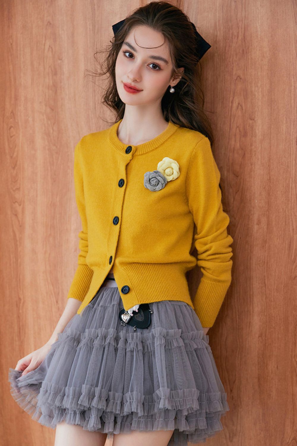 Side angle of mustard yellow cardigan paired with pleated skirt