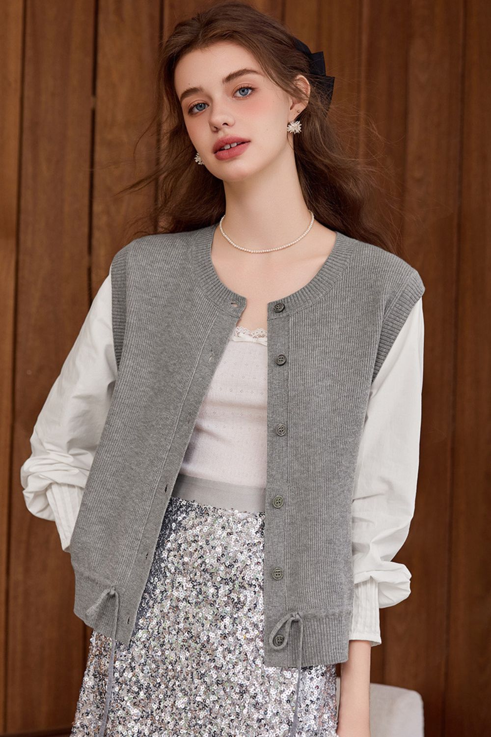 Side view of gray buttoned vest paired with a white blouse and floral skirt