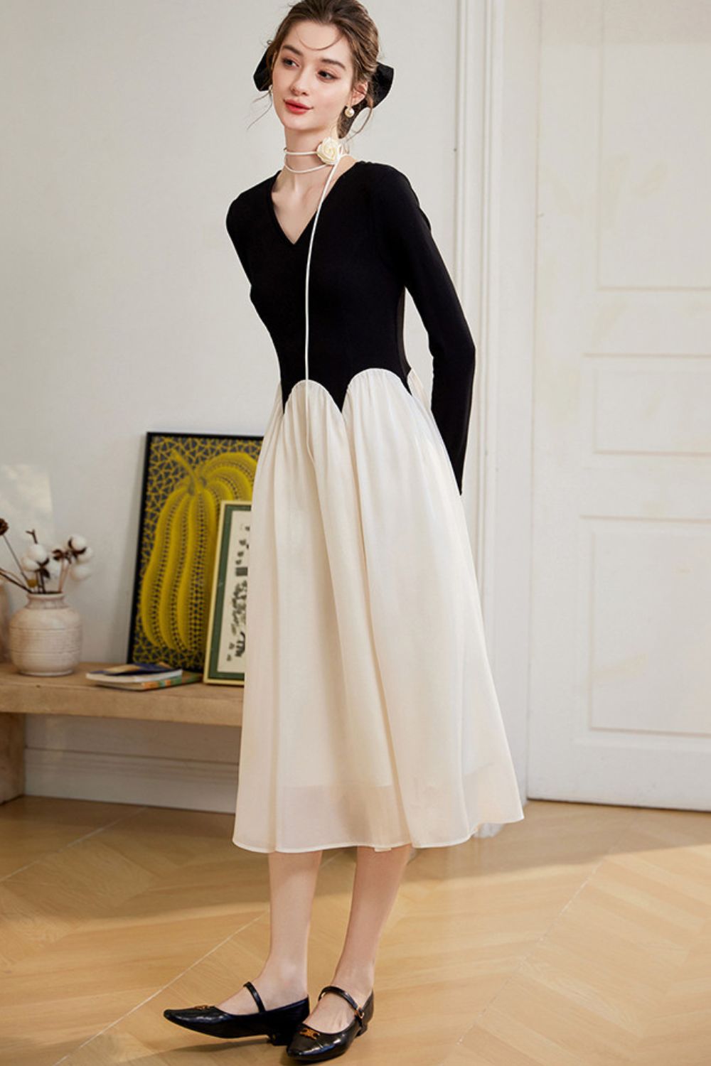 Model showing back view of black top and flowing white skirt