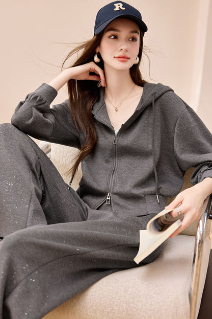 Seated model in gray wide-leg jumpsuit with collar detail, styled with a navy cap