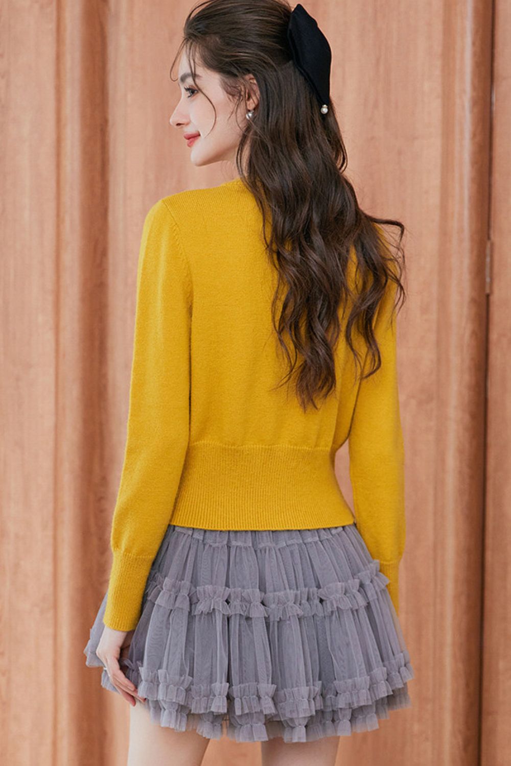 Back view of mustard yellow cardigan styled with gray pleated skirt