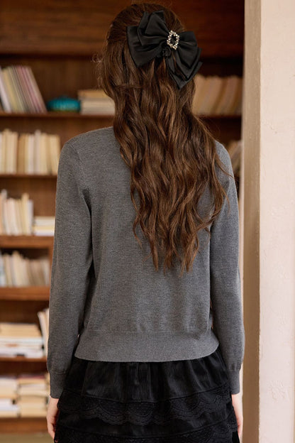 Back view of gray sweater paired with a black ruffle skirt