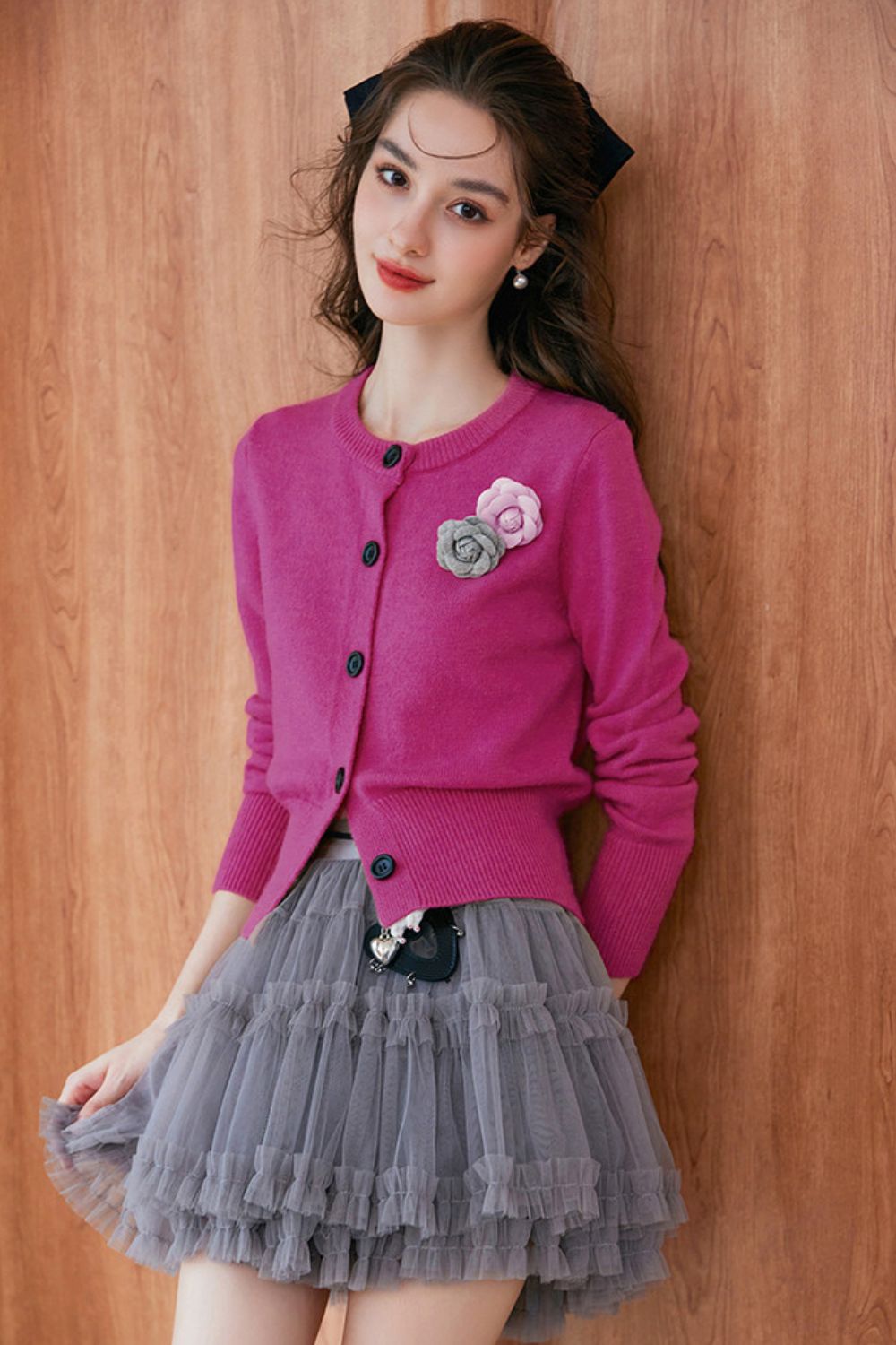 Side profile of pink cardigan with flower brooch, styled with gray skirt