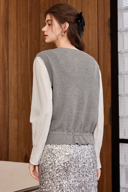 Back view of gray knit vest styled with a white blouse and floral skirt