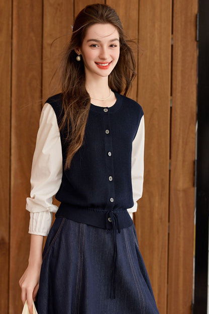 Model wearing a navy blue knit vest over a white blouse and long navy skirt