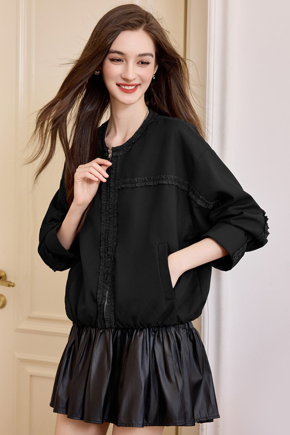 Front view of black jacket paired with black pleated skirt