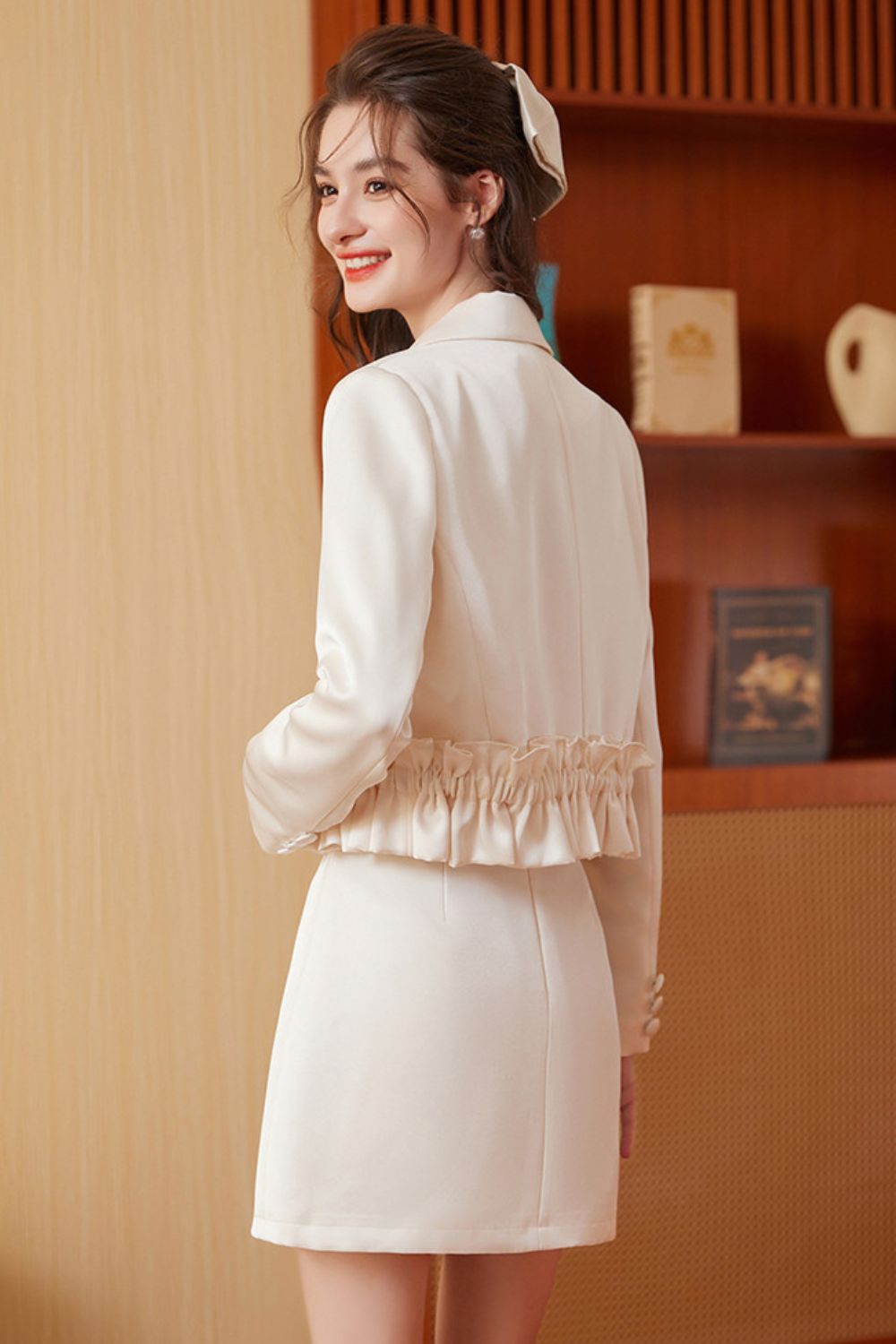 Back view of cream embroidered tassel jacket with cream mini skirt