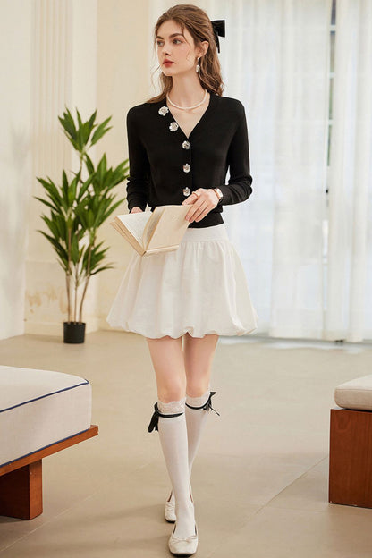 Full-body view of black pearl-button cardigan with white skirt and knee-high socks